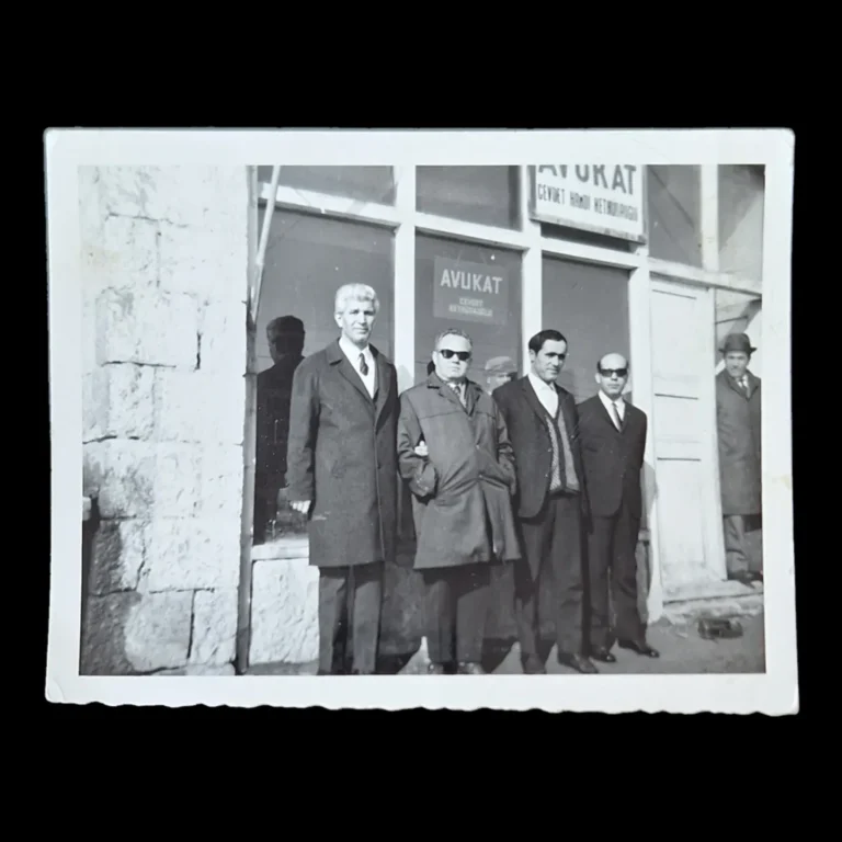 Men in overcoats and suits posing in front of an office with the sign 'Avukat Cevdet Hamdi Kethüdaoğlu'