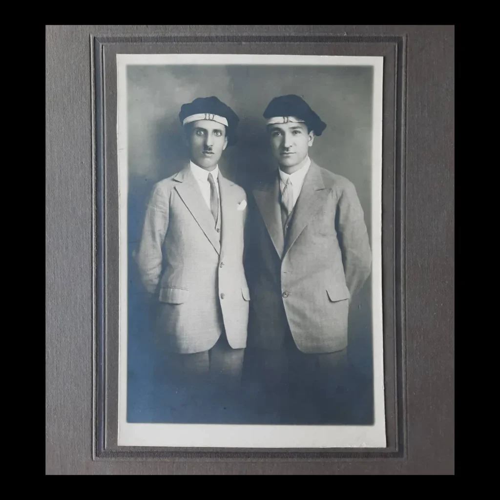 Mounted studio photograph of two young people in light-colored suits and banded berets
