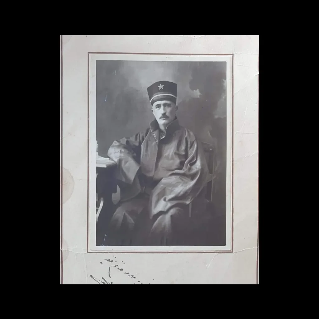 Mounted portrait of a judge in a starred cap and robe, seated beside a desk