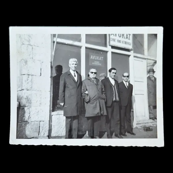 Hombres con abrigo y traje posando frente a un despacho con el letrero 'Avukat Cevdet Hamdi Kethüdaoğlu'