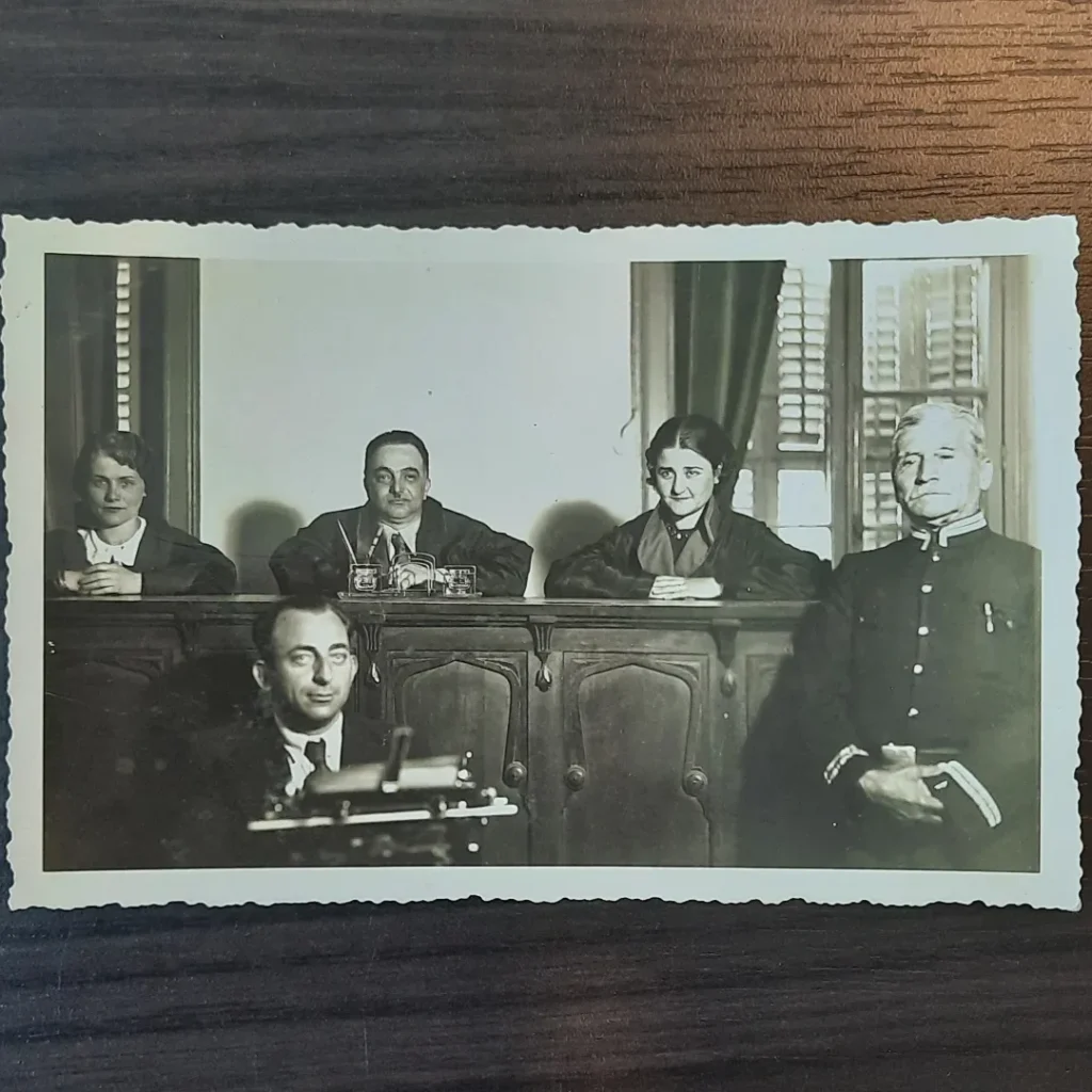 Kürsüde üç kişilik heyet (ikisi kadın), önde daktilo başında kâtip, sağda üniformalı mübaşir