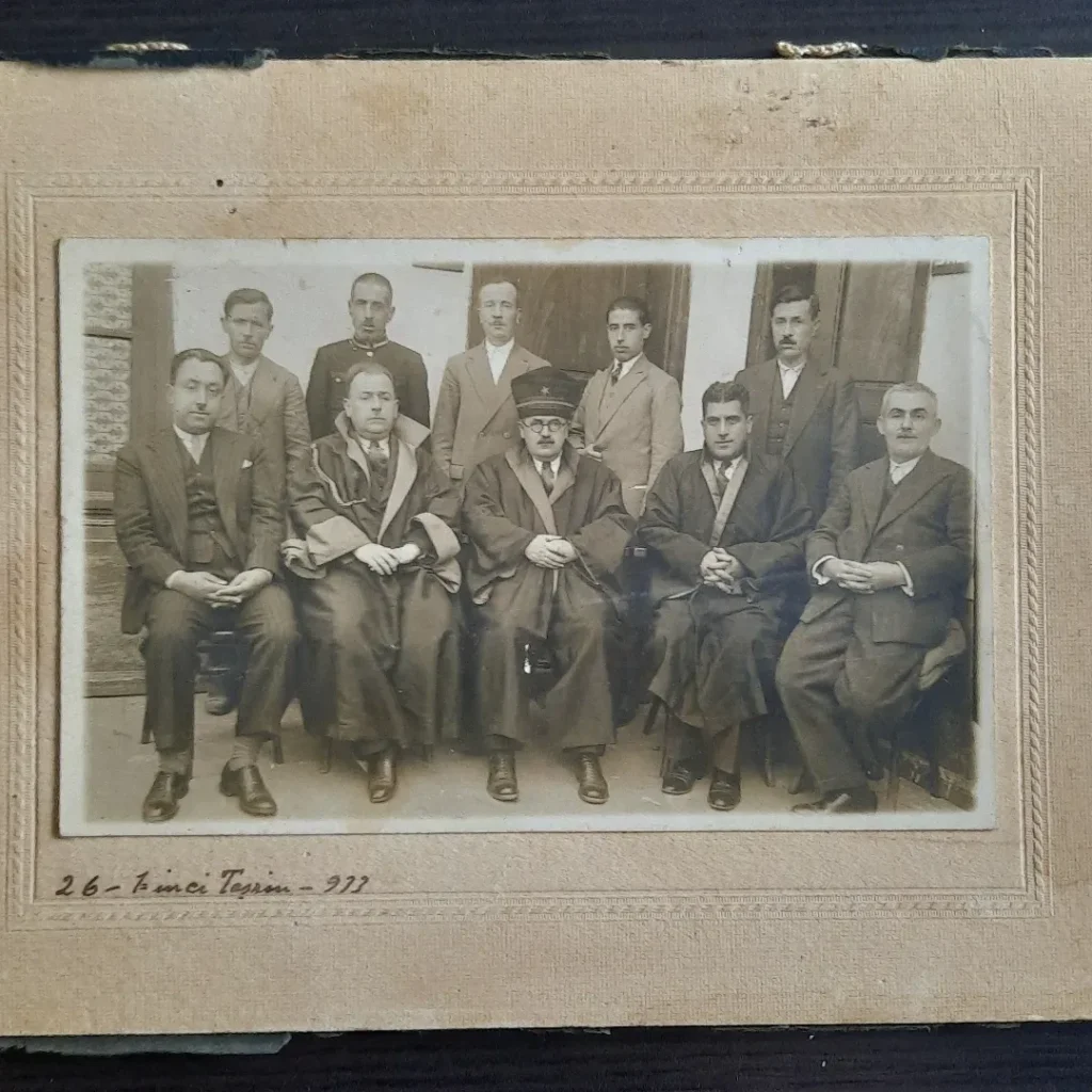 Ön sırada cübbeli üç kişinin oturduğu mahkeme heyetinin kartona monte fotoğrafı ve alttaki el yazısı tarih