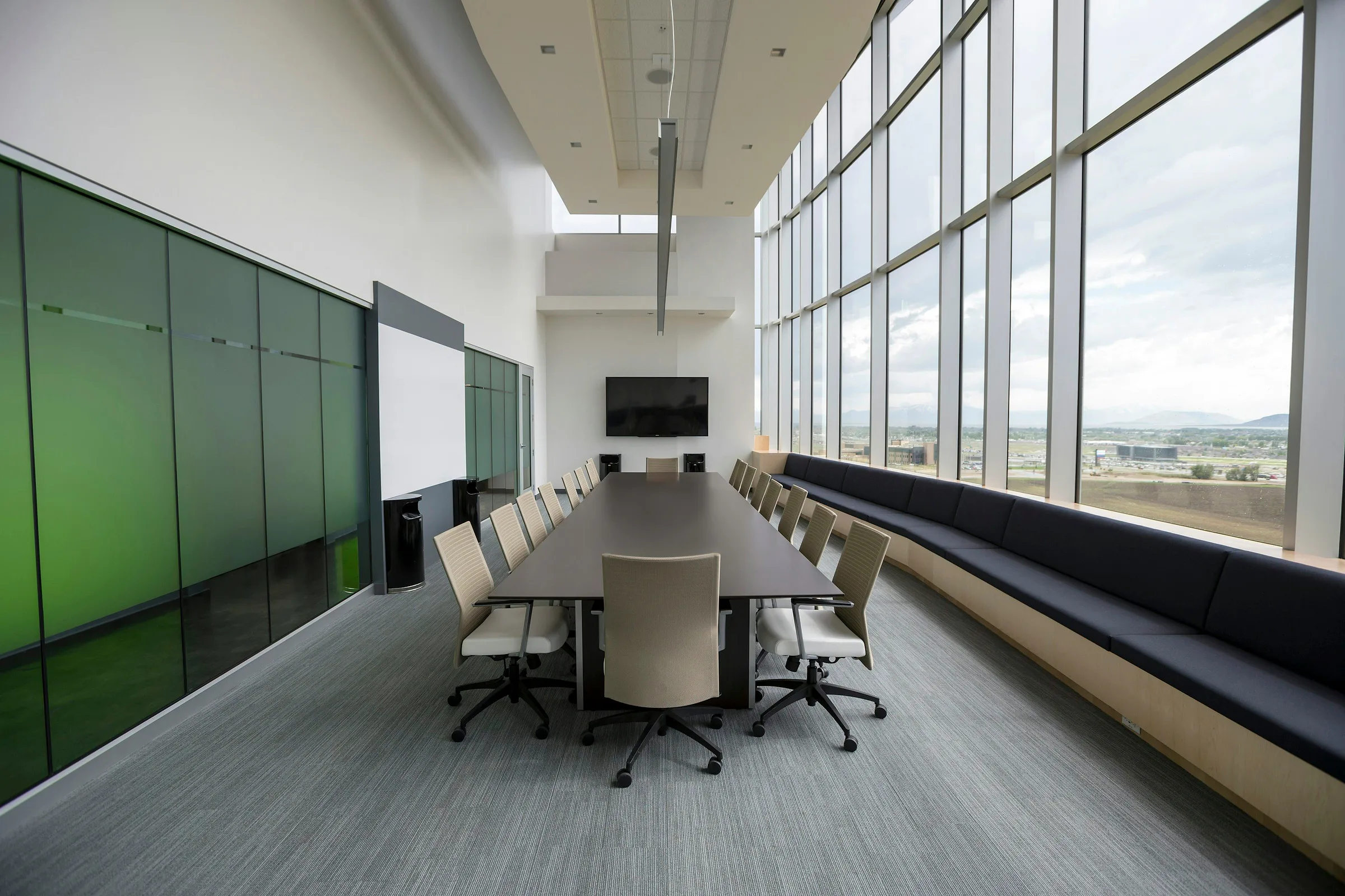 Empty meeting room with full-height windows, a long table and navy-blue bench seating