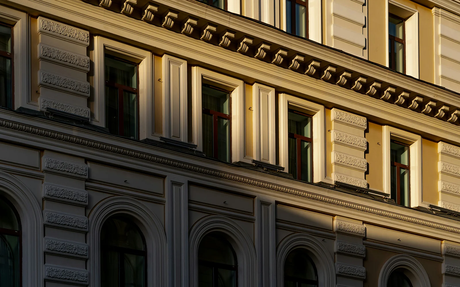 Cornisa y ornamentos de ventanas en la fachada soleada de un edificio clásico