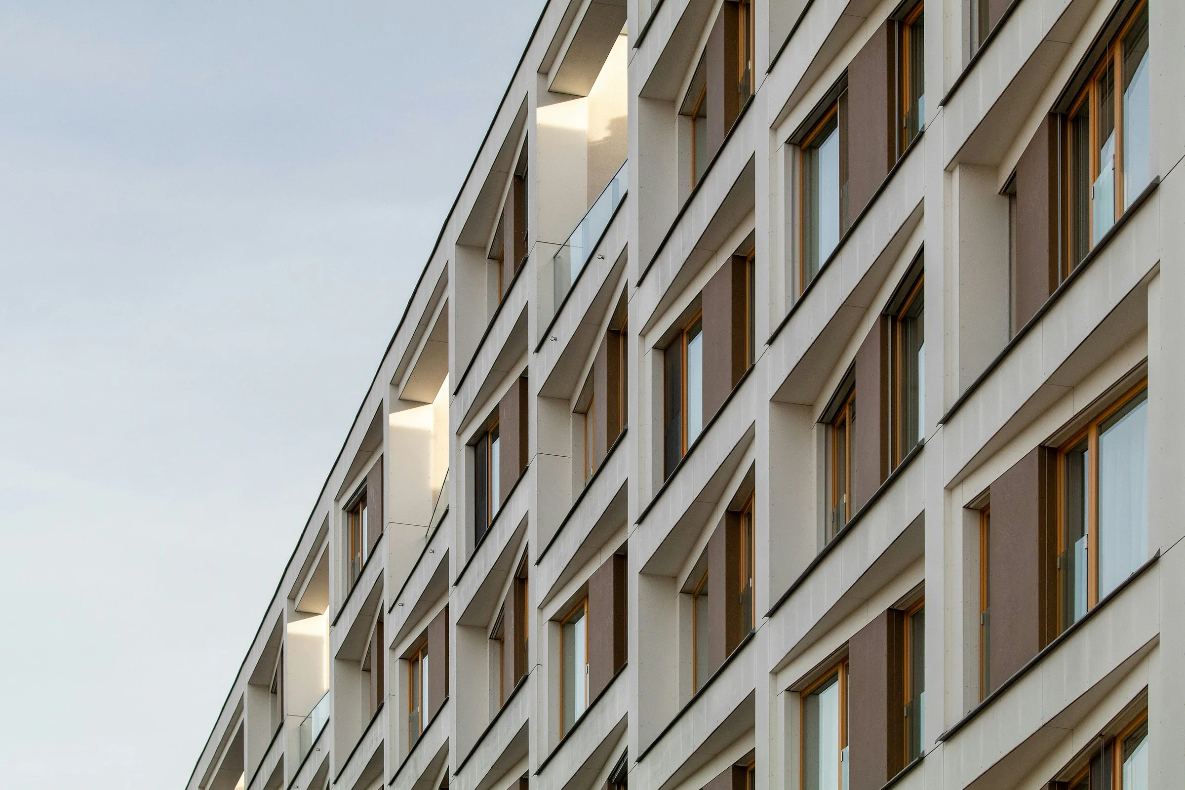 Fachada residencial moderna de color crema con vanos de ventana profundos