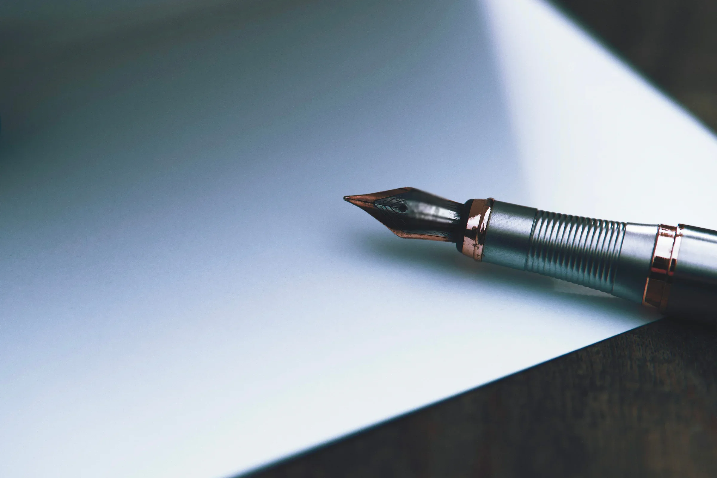 Steel-bodied fountain pen resting on white paper