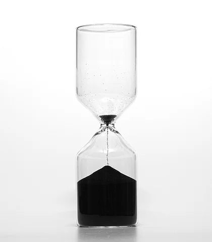 A simple cylindrical hourglass with black sand running through it, on a white background