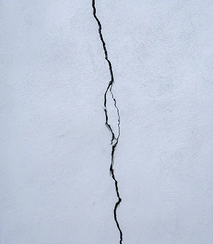 Deep crack running the full length of a light-colored plastered wall