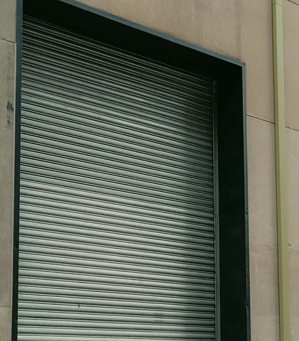 Lowered gray metal shutter of business premises with a stone facade